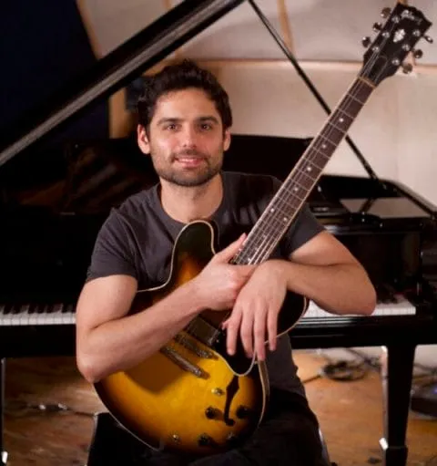 Daniel Weiss holding a guitar, conveying warmth and passion